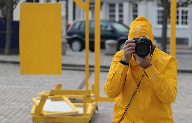 A person wearing a yellow coat taking a photo