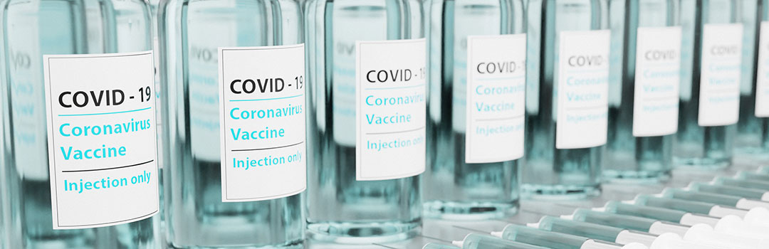 A row of Covid-19 vaccine vials with syringes