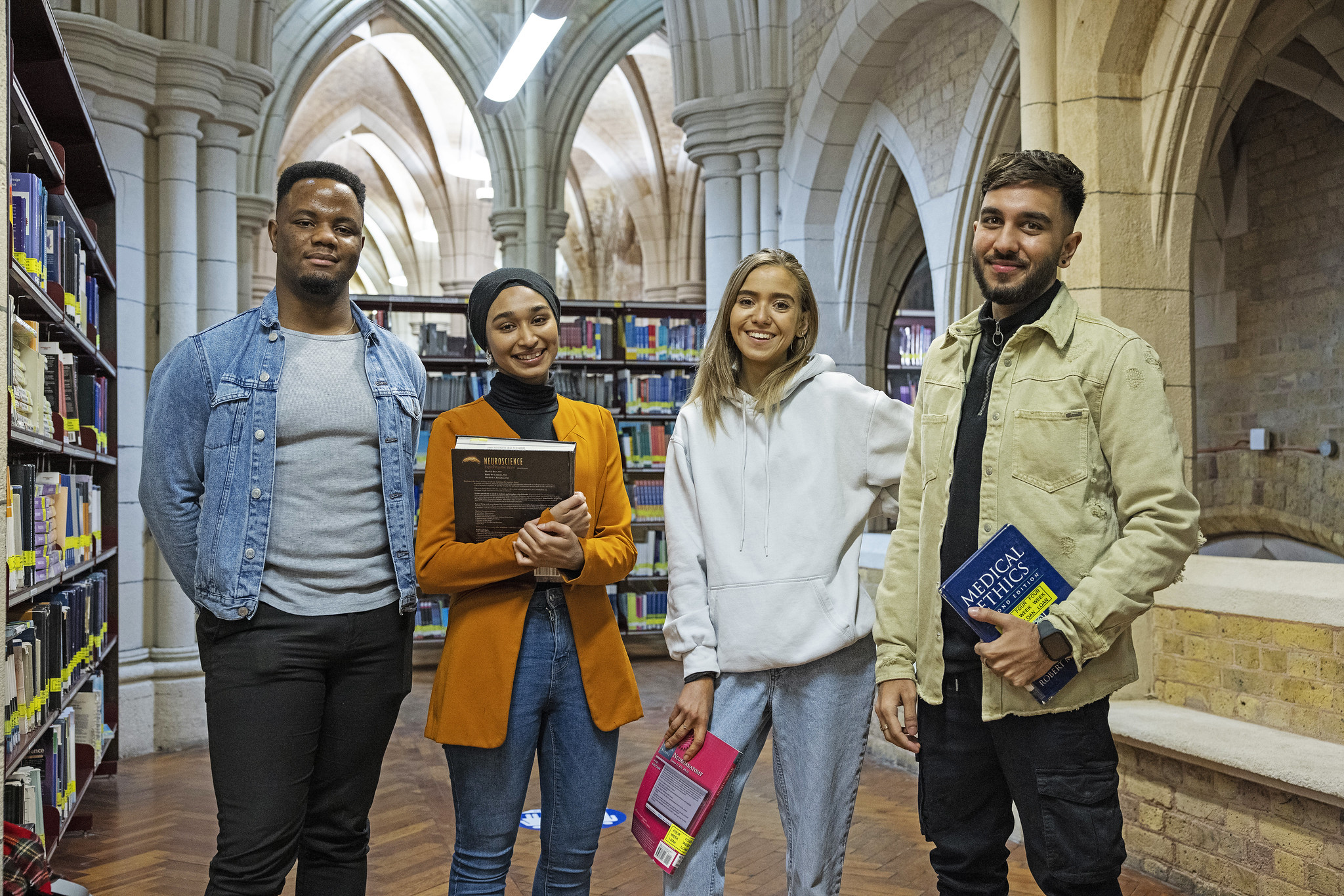 Four students standing in the library at Whitechapel