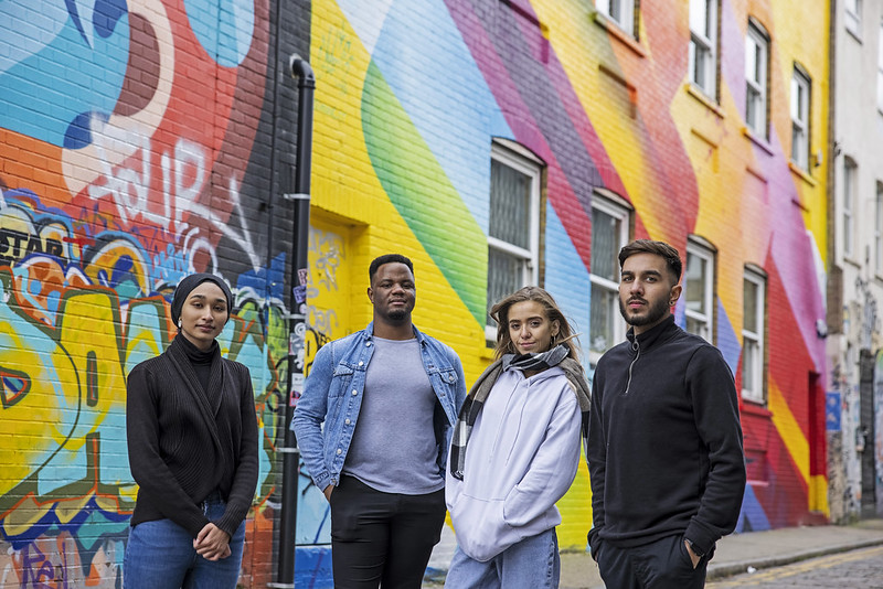 Four students standing in front of a colourful mural