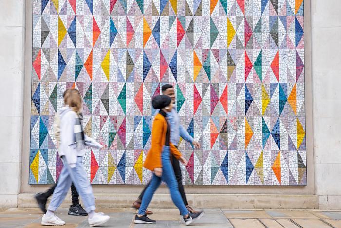 Students walking in front of a colourful wall