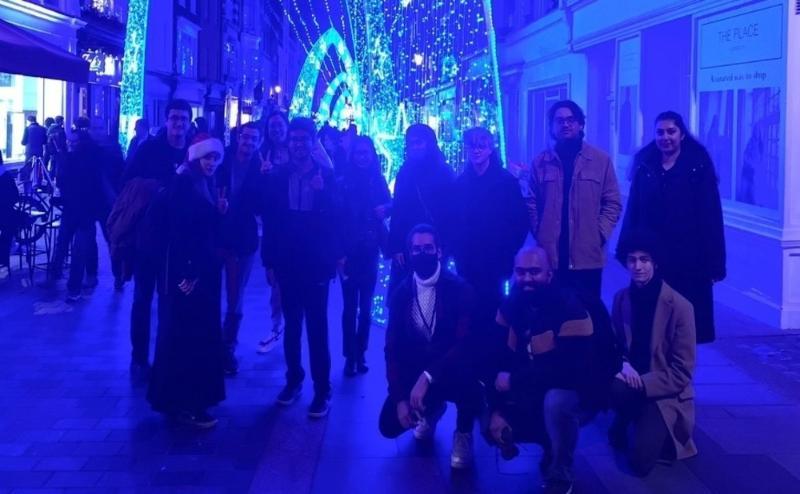 a group of Queen Mary students in front of a display of blue and white Christmas lights
