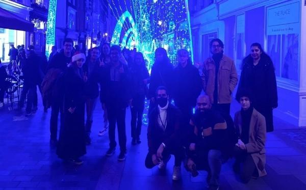 a group of Queen Mary students in front of a display of blue and white Christmas lights