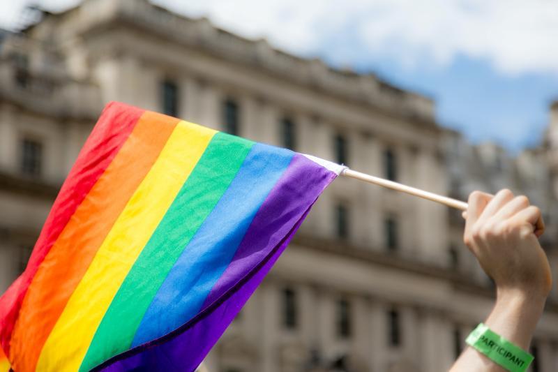 A hand holding a rainbow flag