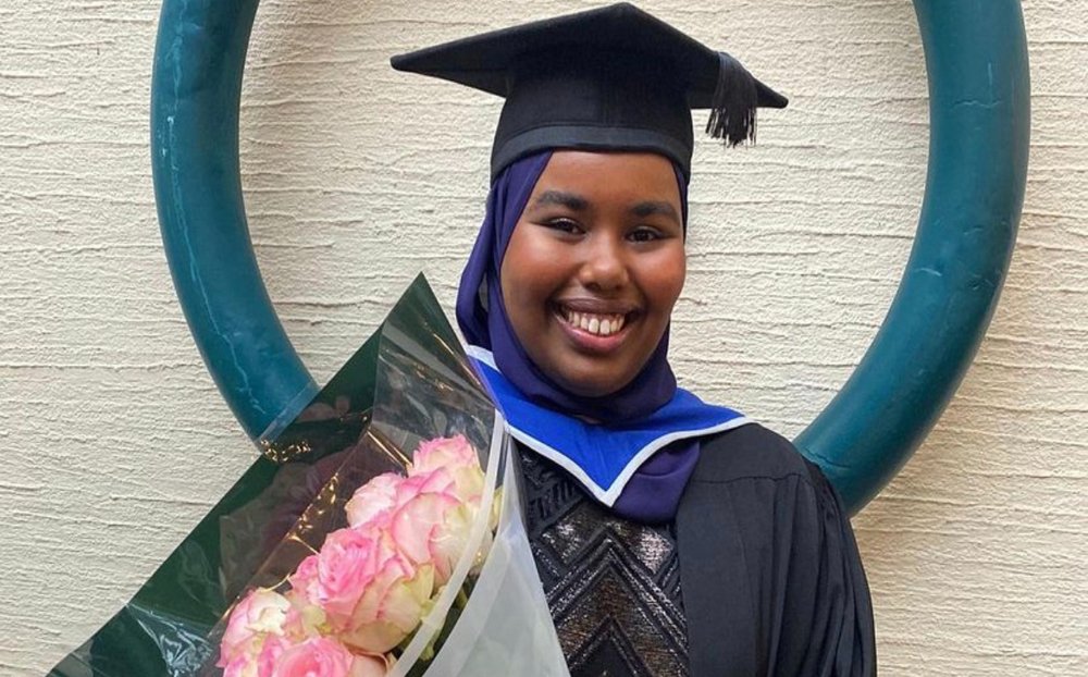 Queen Mary student Safia at her graduation holding a bunch of pink roses
