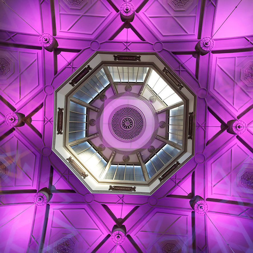A view from below of the ceiling of the Octagon in purple light