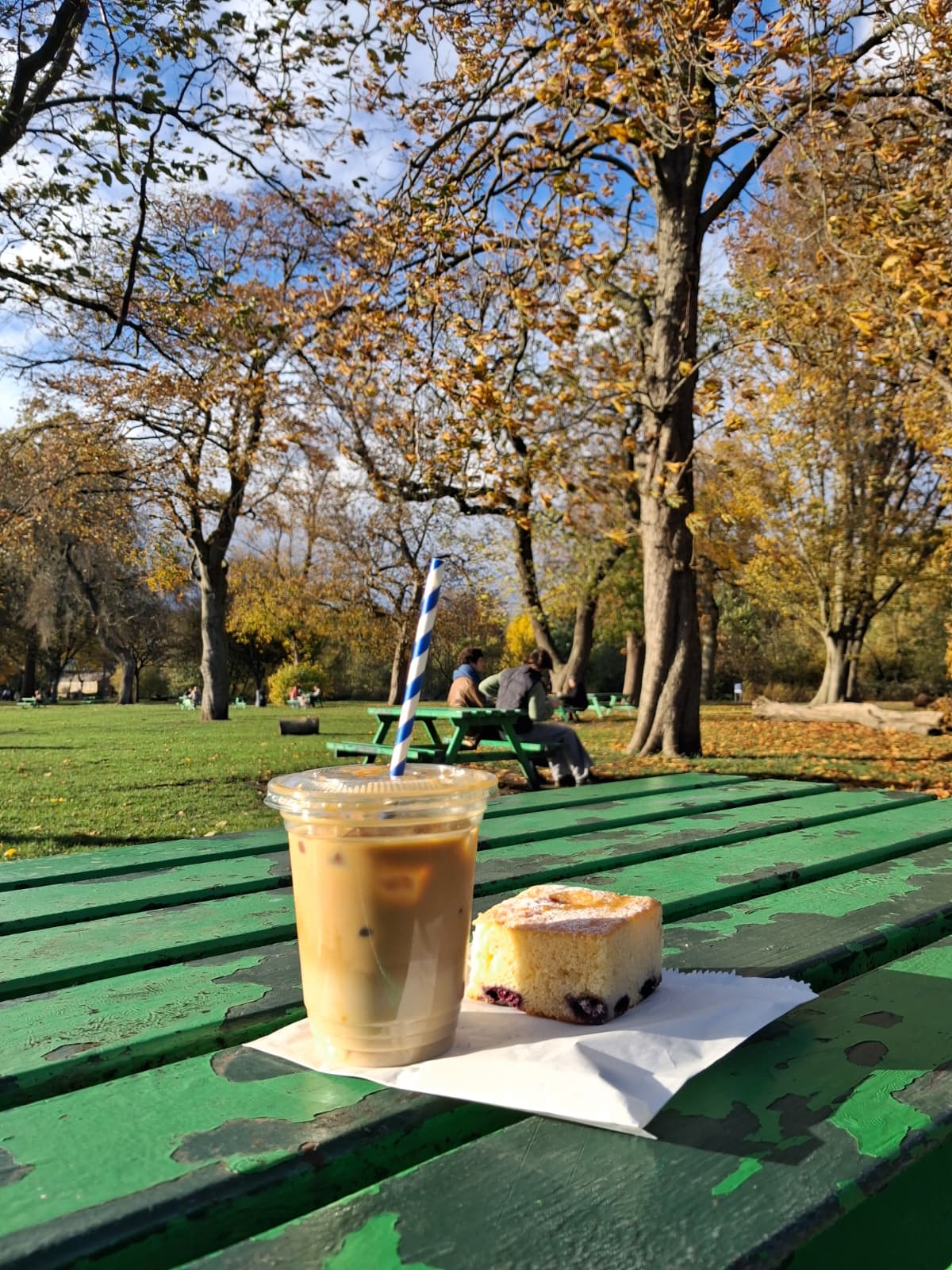 Image of a coffee and a cake in a warm autumn sunny park day