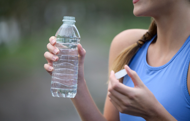 Woman holding plastic water bottle after workout