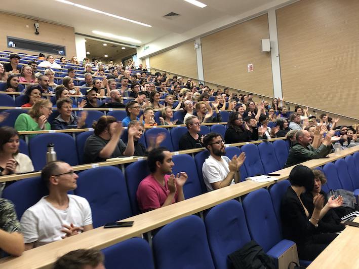 An audience applauding in a lecture theatre