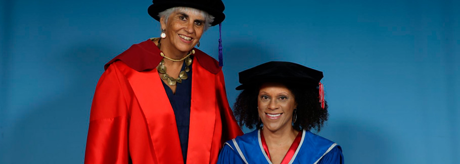 Bernardine Evaristo sits on right and wears a Doctoral hat and robe.