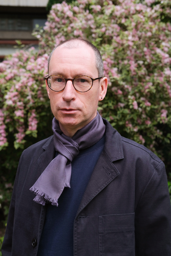 Brian Dillon is a white man with brown glasses. He wears dark blue jacket and scarf.