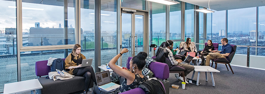 Students sit on sofas on the 7th floor of the Graduate Centre with view over the skyscrapers of the City of London