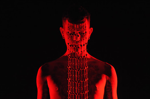 Dominic Johnson performs in red silhouette against a black background