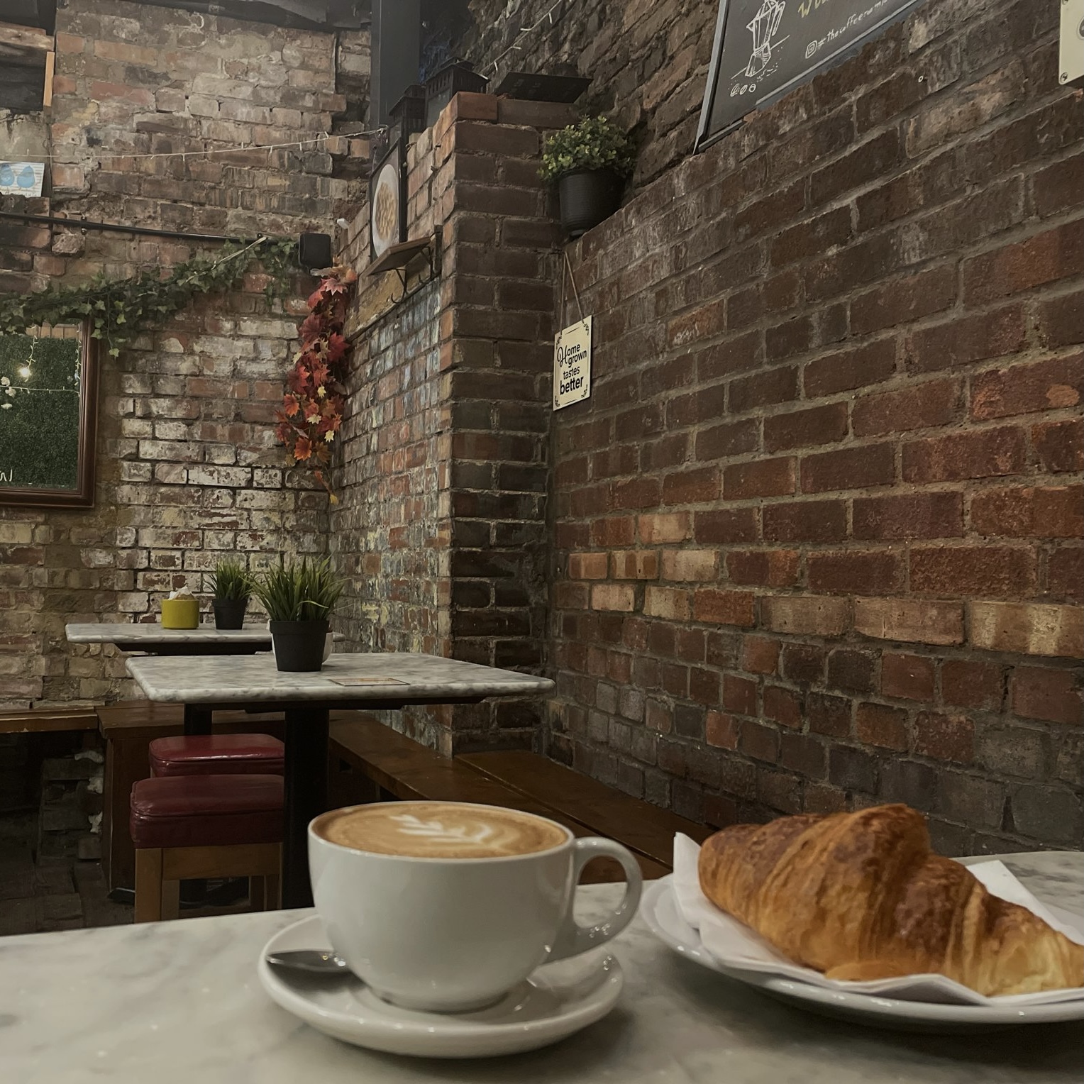 An image of a table inside a cafe with coffee and a pasty on it