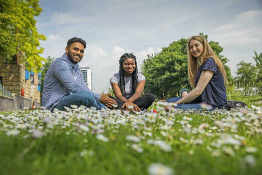 Queen Mary University of London students sitting on the grass at our Mile End campus