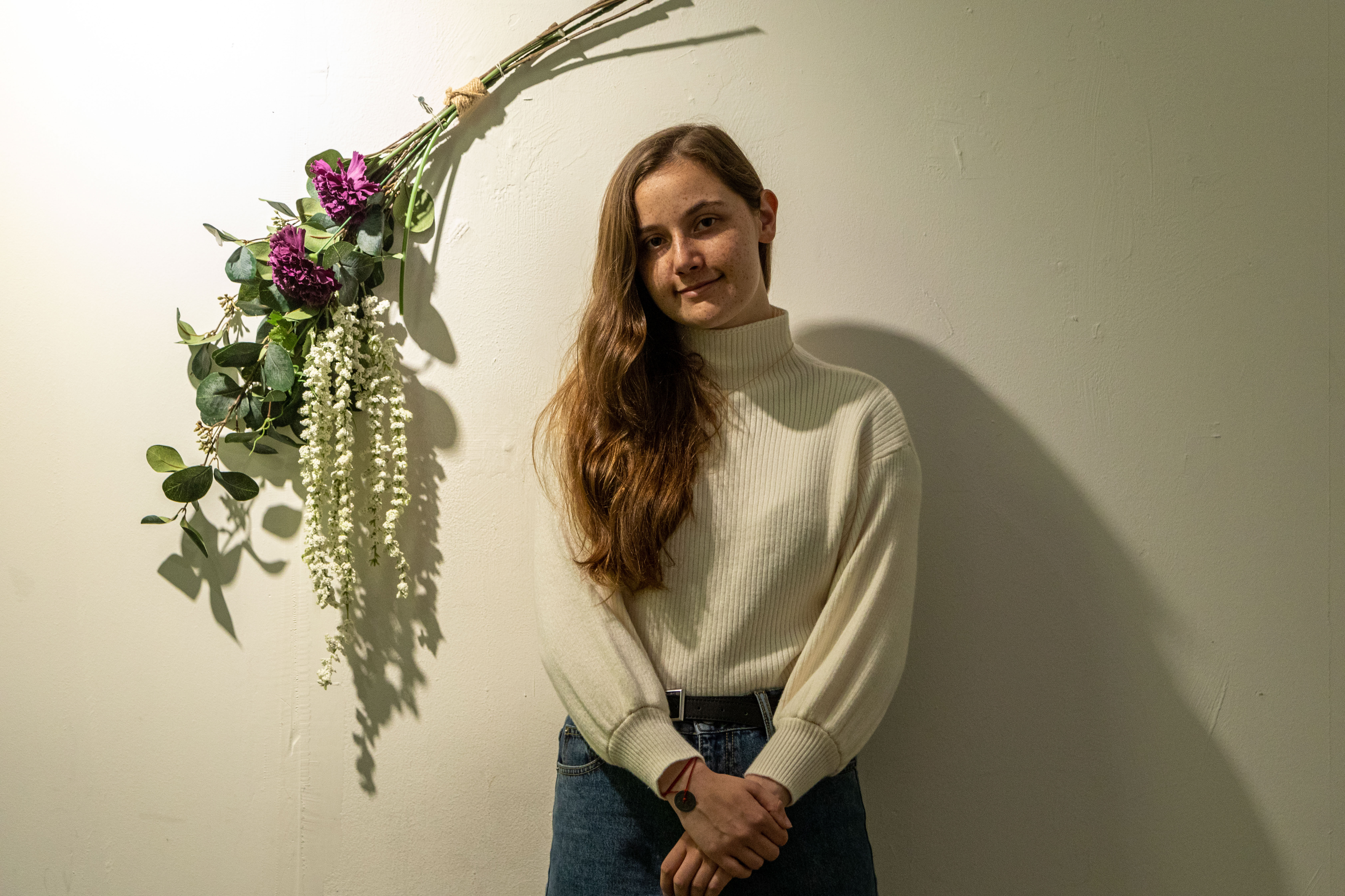 photo of student standing with flowers behind smiling
