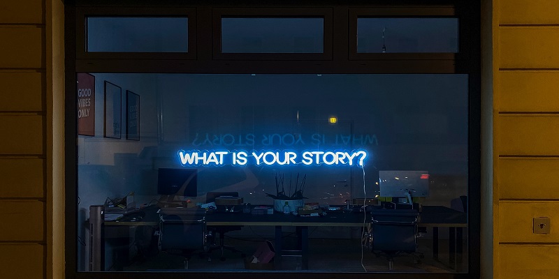 A neon sign saying 'what is your story'