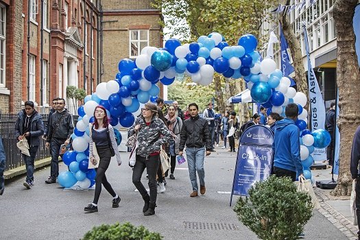 Students on the Queen Mary Mile End Campus going under a balloon arch