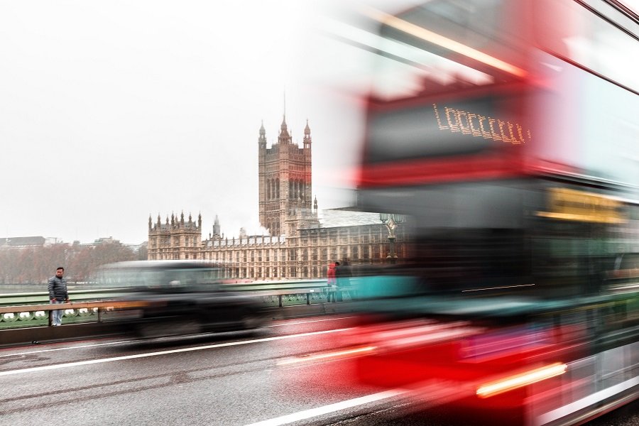 blurred image of a London bus going pas the Houses of Parliament across Westminster Bridge in London