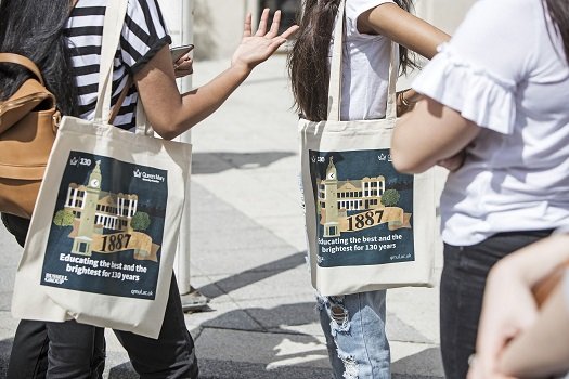 a cropped shot of some students with bags showing tote bags commemorating the 130 year anniversary of Queen Mary University