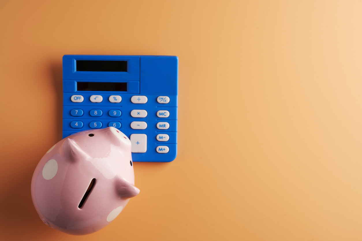 Piggybank lying on top of a calculator