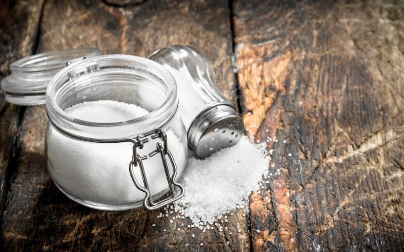 a jar of salt and a salt shaker on a wooden surface