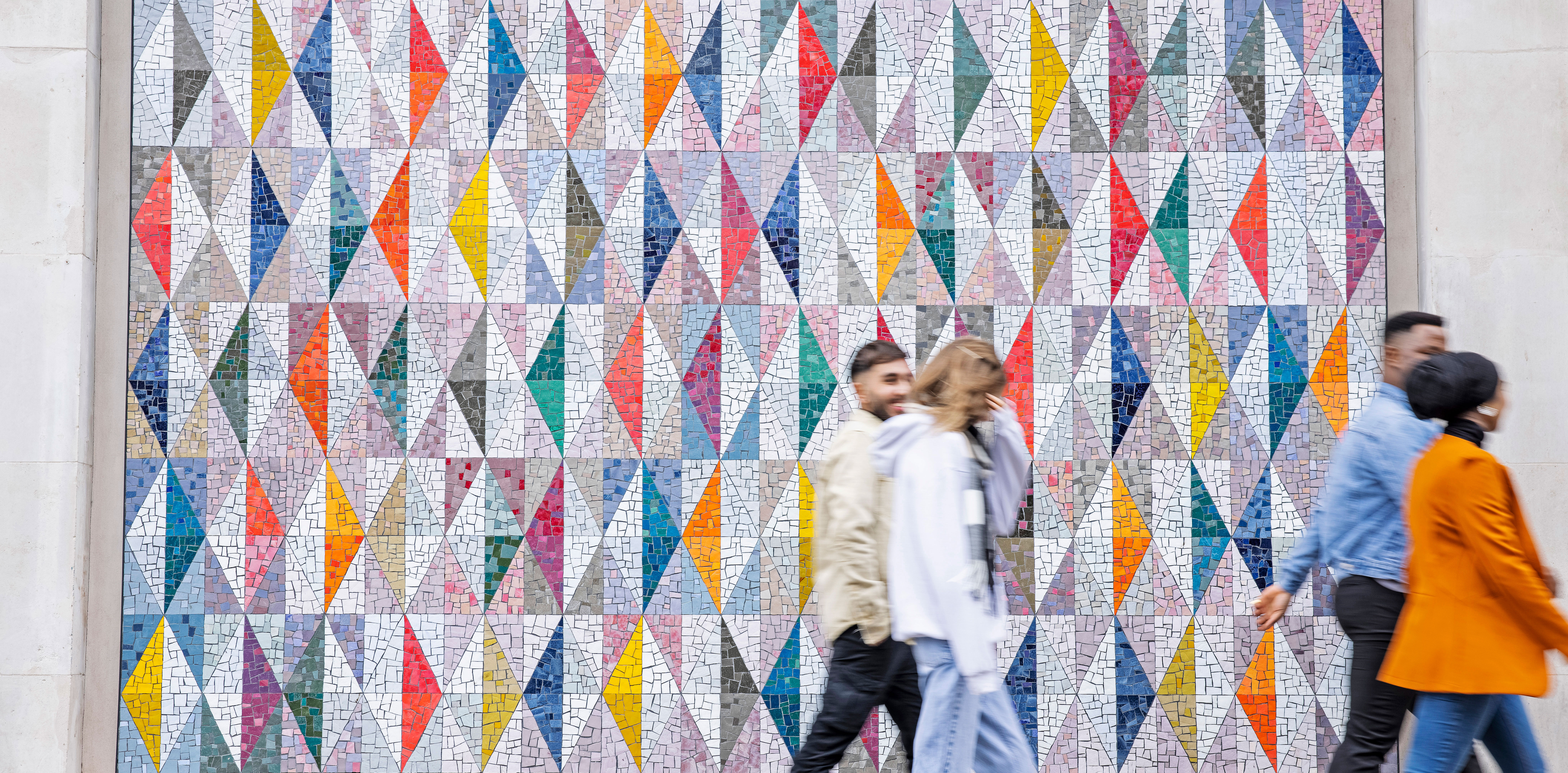 Students passing by a colourful wall display