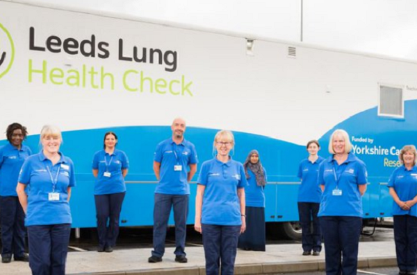 Staff stand in front of the Leeds Lung Health Check mobile screening unit.