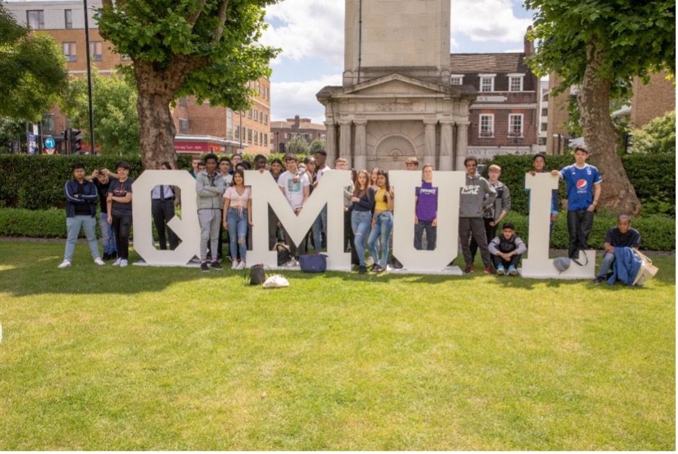 Students posing by the QMUL logo