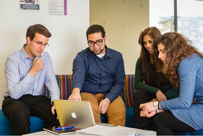 Four people looking at a laptop