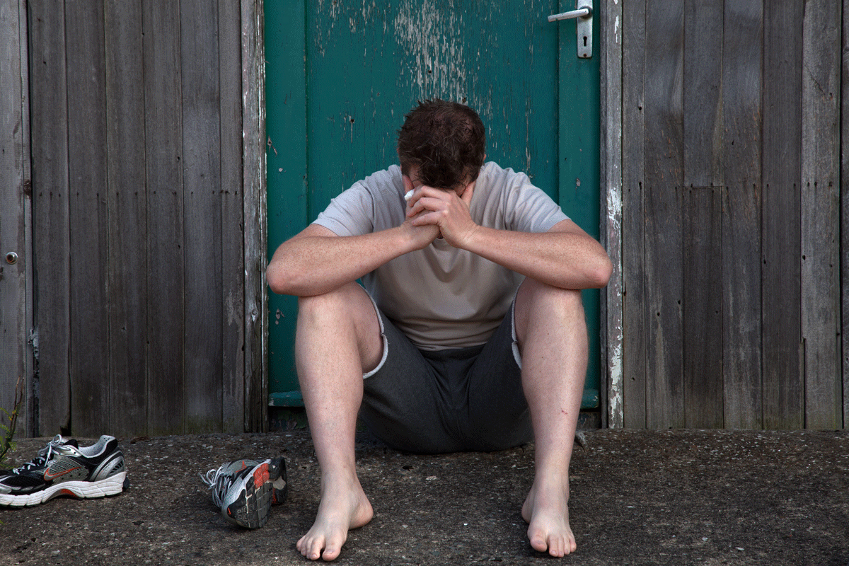 A man holds his head in his hands, as he experiences mental health difficulties